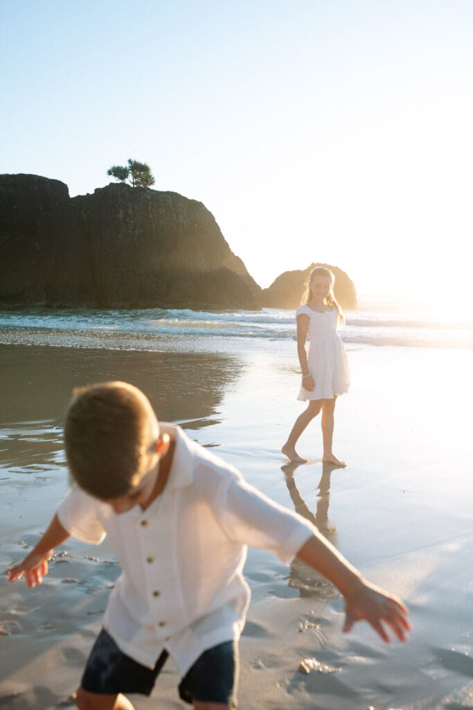 A beautiful sunrise at Dreamtime Beach, NSW .Siblings are playing in the shining water and sand. The rocks and waves are in the background
