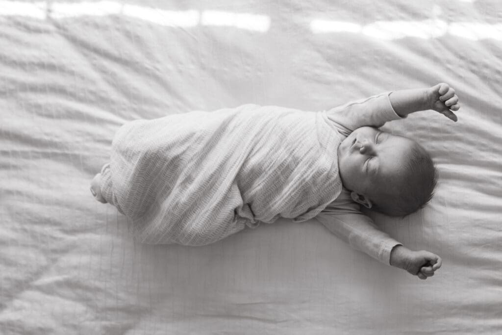 A newborn stretches out after a nap on a bed in a bright Byron Bay bay home