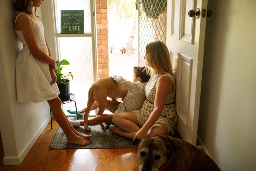 A family sits in the doorway with their dogs in a gold coast home , they are close and cuddly