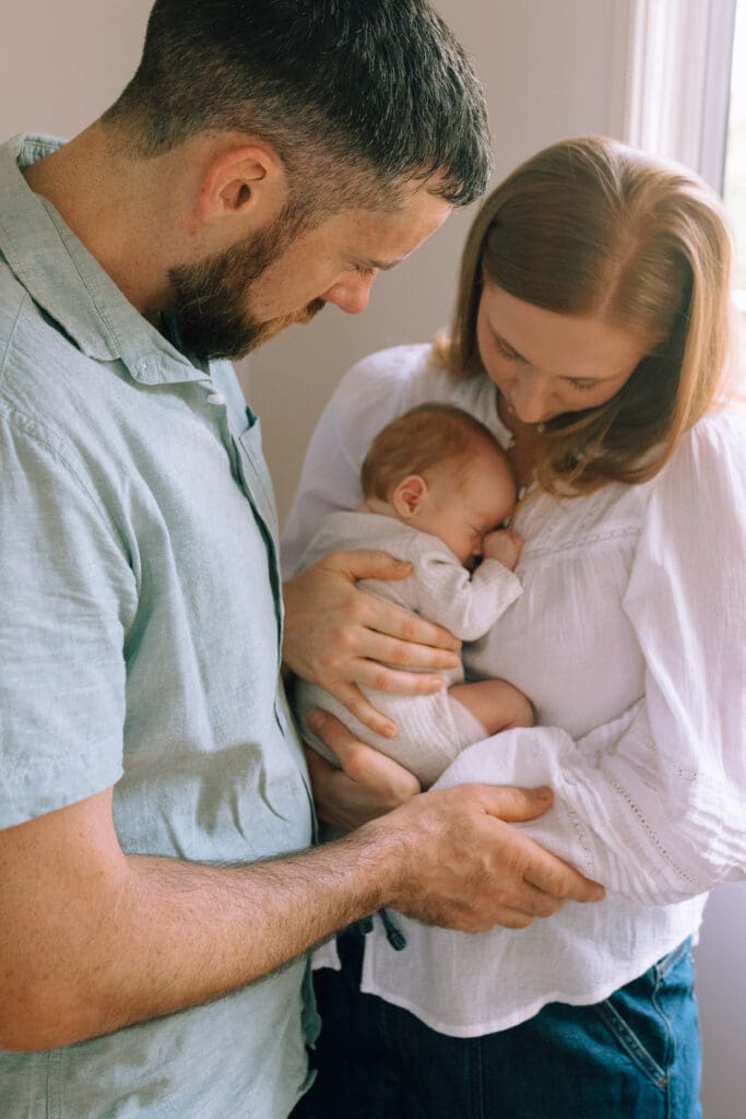 New parents hold their newborn baby girl next to a window in their Northern Rivers home