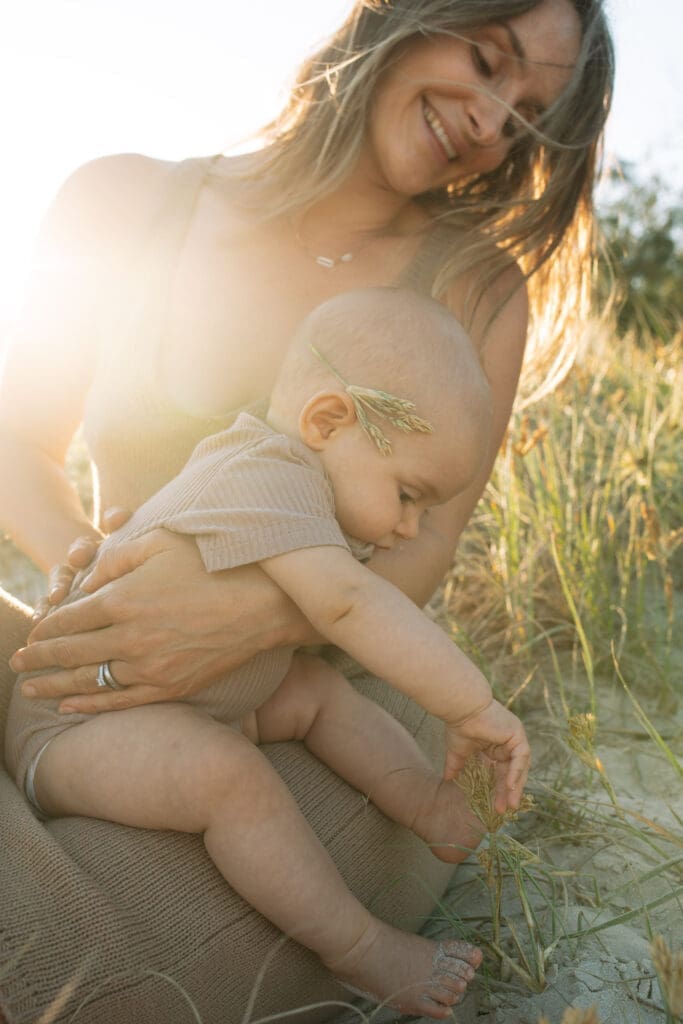 A mother and baby cuddle in the afternoon light in the dunes at Hastings Headland