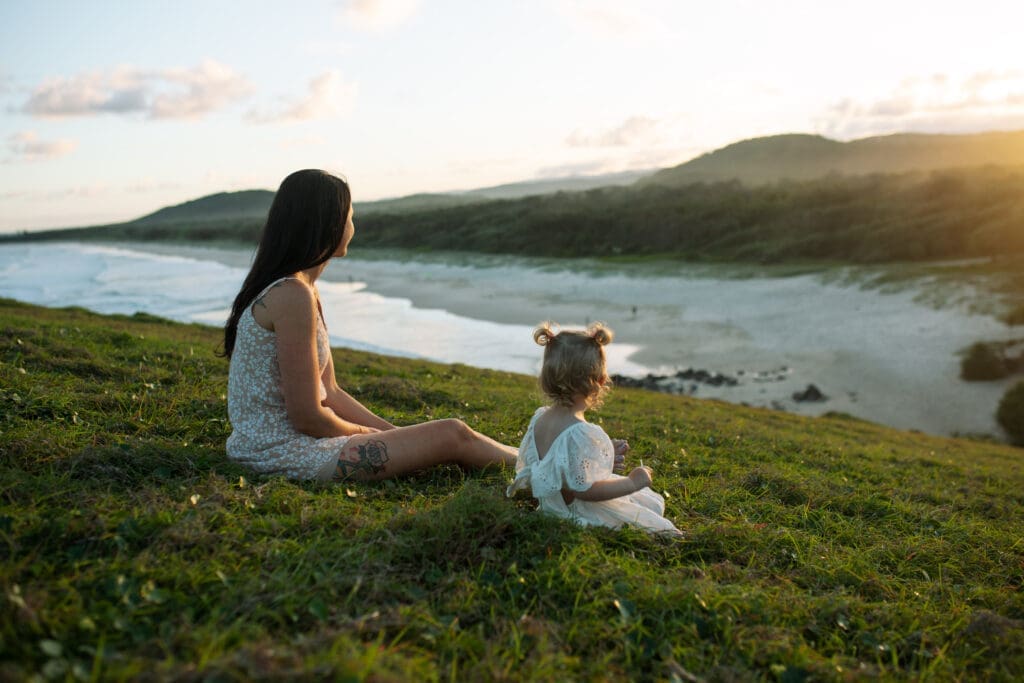 Mother and toddler sitting together on Norries Headland during a sunset family photography session in Cabarita