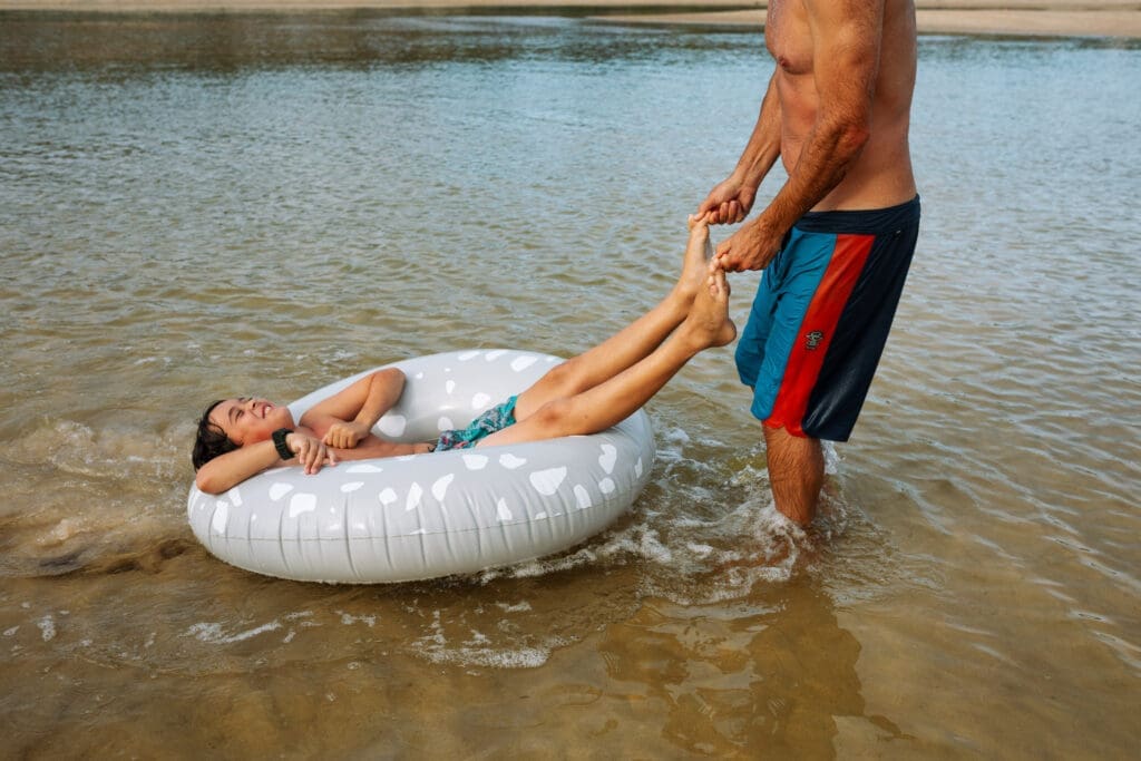 A father pulls his son by the toes on Hastings creek on a summer afternoon