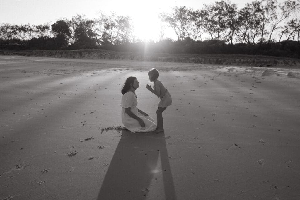 A child is excitedly talking to her mother , the sunset is shining through beach sand dunes and casaurina trees at Black Rock Beach Pottsville