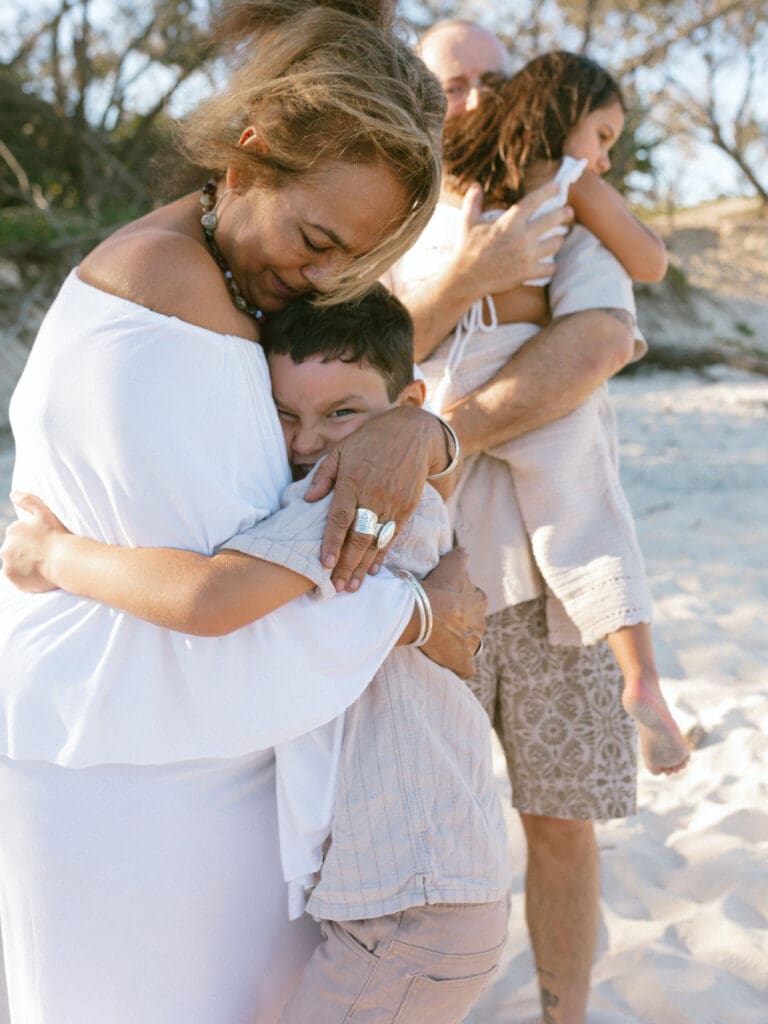 Grandmother and grandson embracing on the beach during a candid Kingscliff family photography session