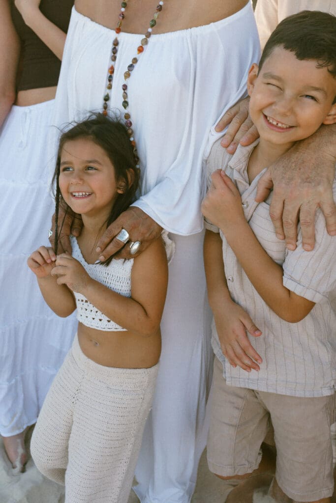 Candid close-up of a boy laughing with his sister and extended family gathered around him on the Tweed Coast