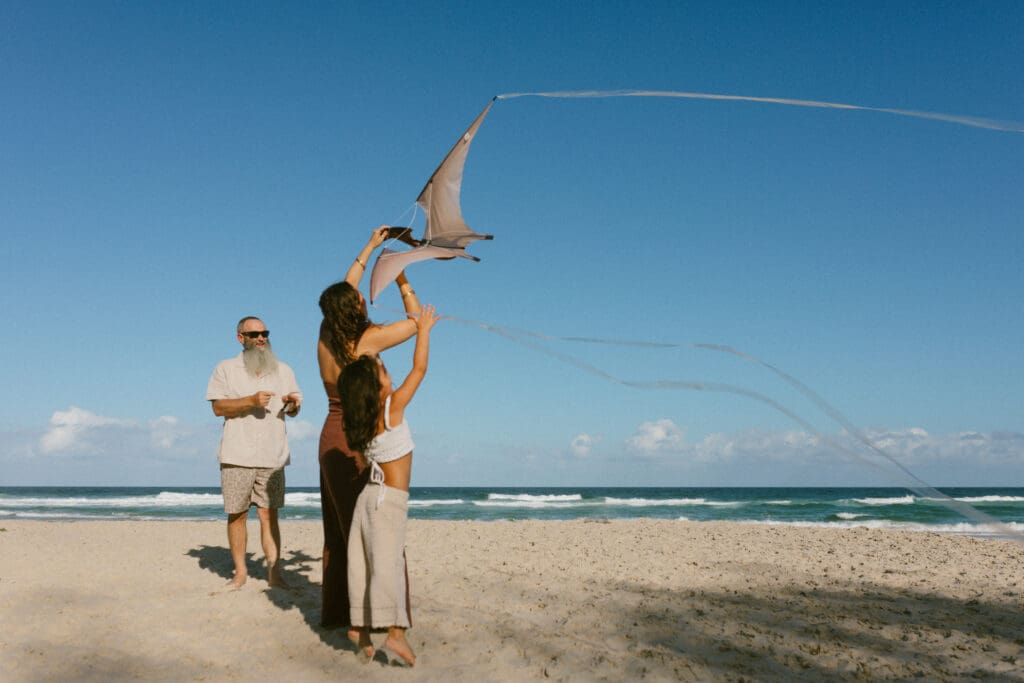 Family flying a kite together on Kingscliff beach during a natural, candid family photography sessio