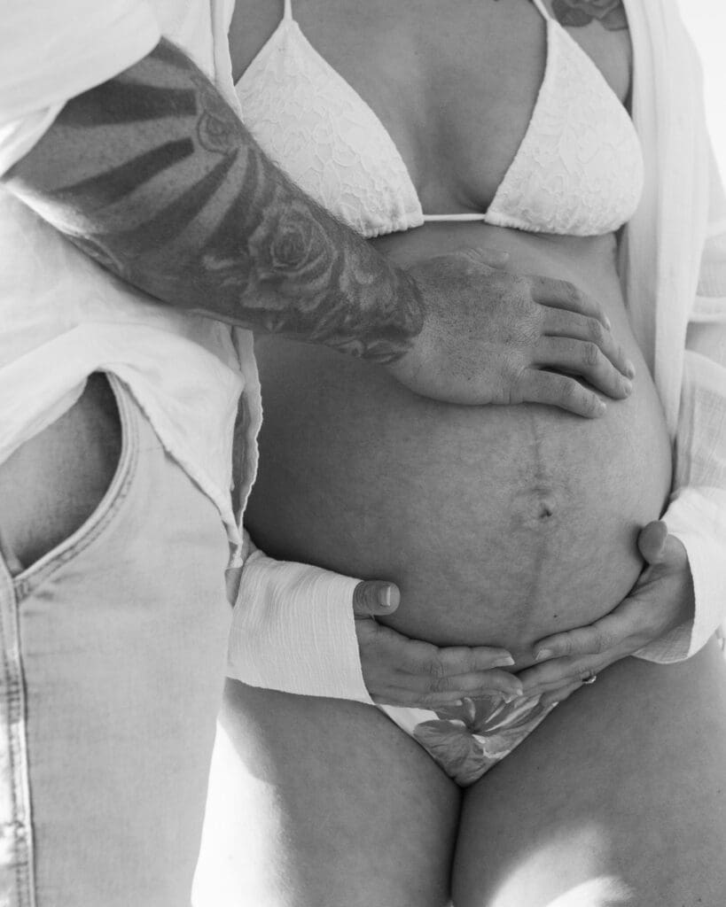 Black-and-white portrait of an expectant couple during their babymoon maternity session at Belongil Beach, Byron Ba
